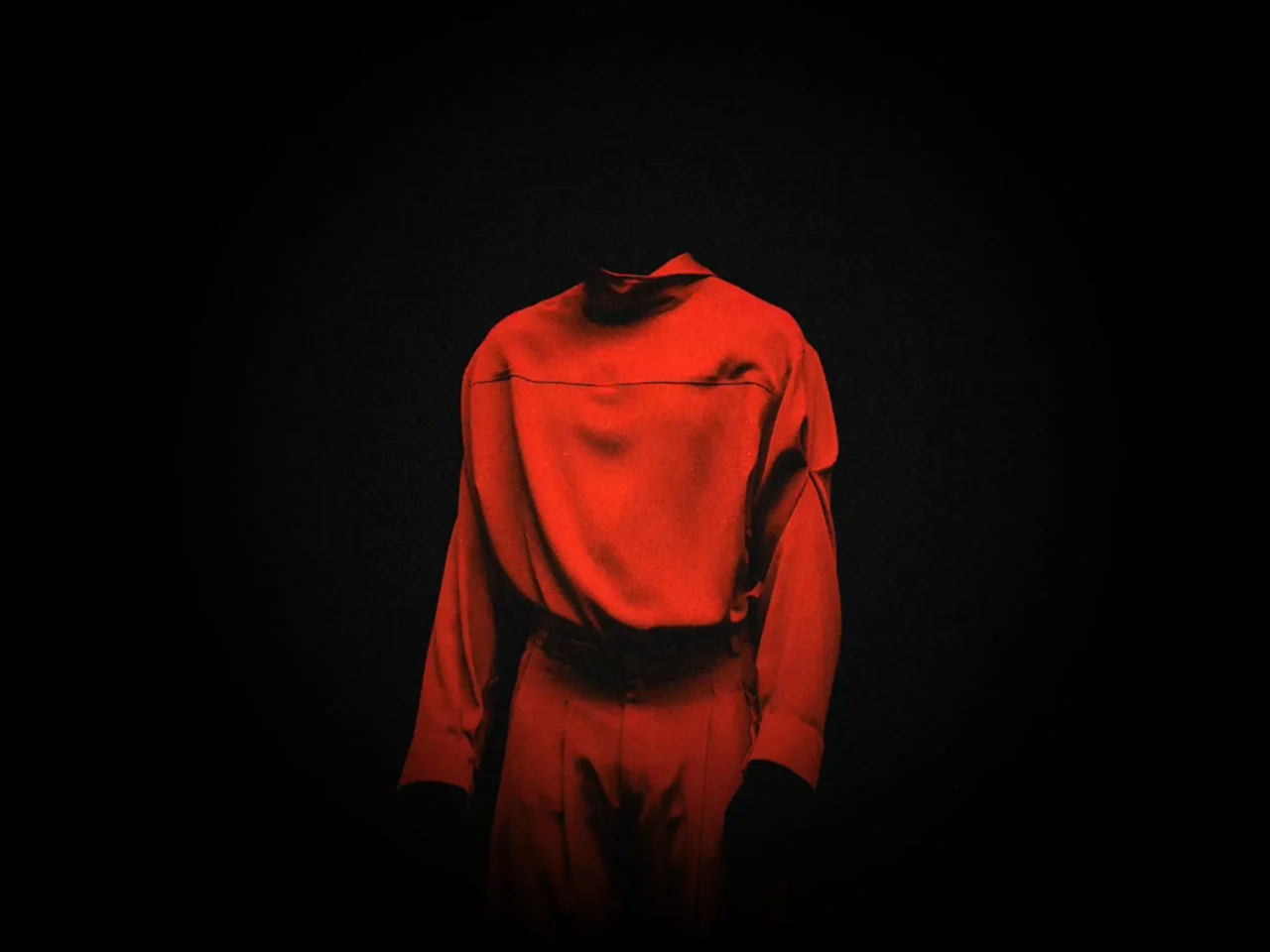 Headless figure wearing a red long-sleeve shirt against a black background. The person stands with arms by the sides.