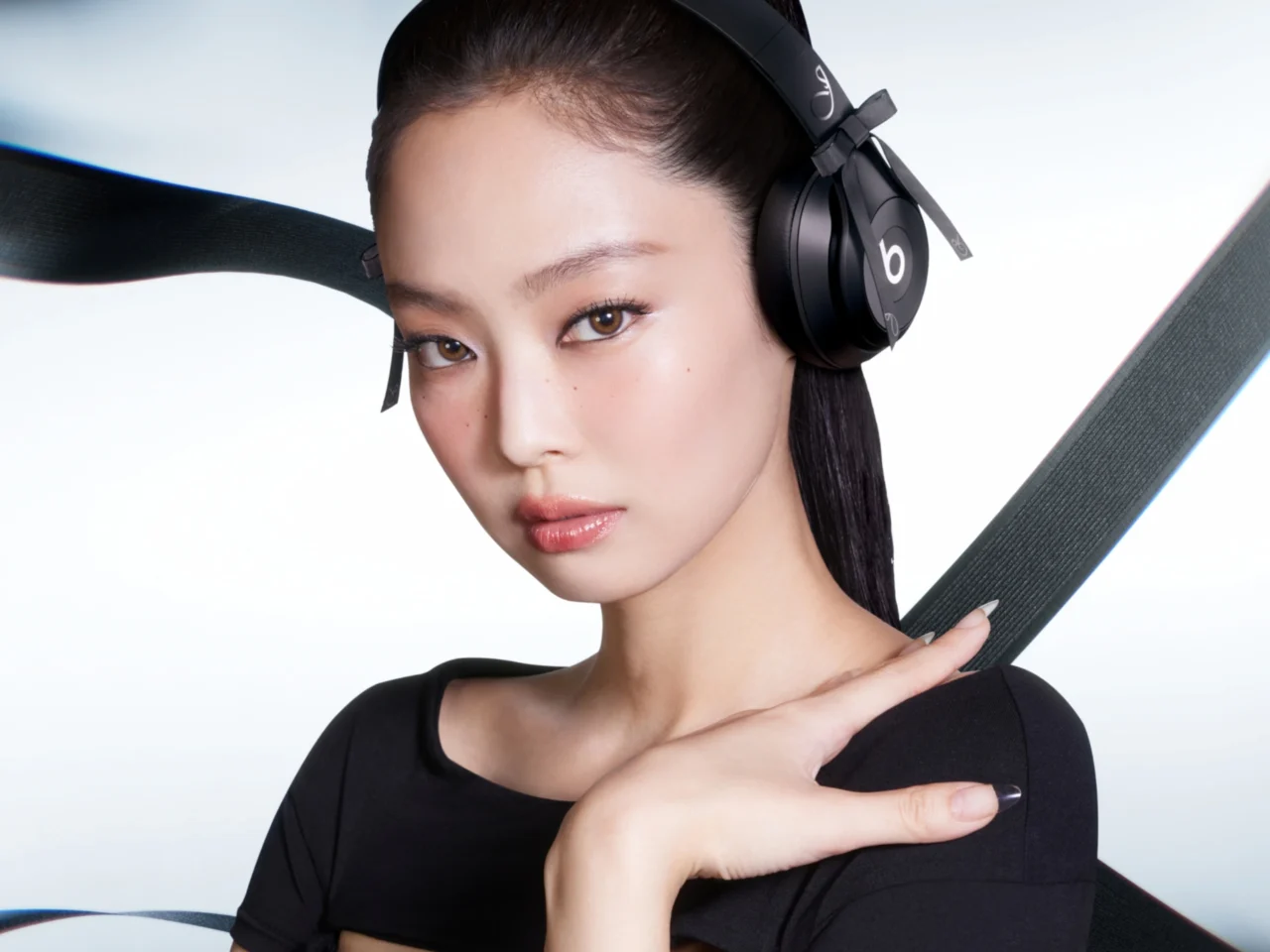Woman wearing black over-ear headphones, looking at the camera with a neutral expression.