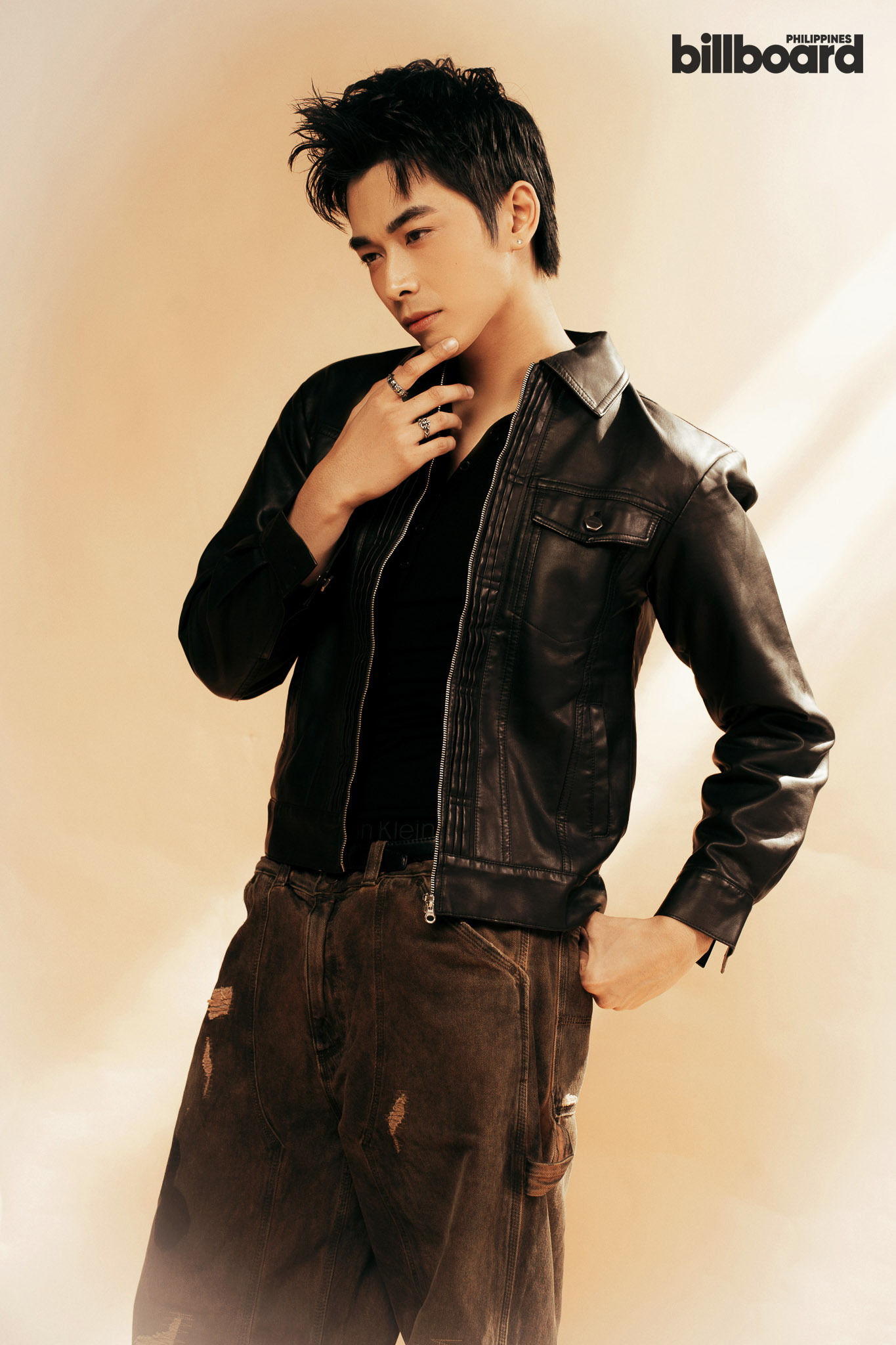 Young man in a black leather jacket poses with his hand on his chin against a warm beige backdrop; 'billboard Philippines' logo in the top-right corner.