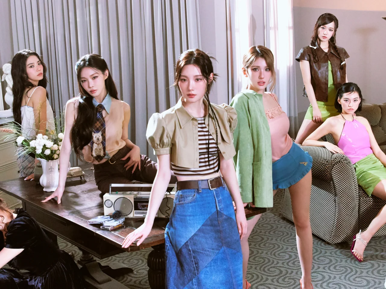 Group of stylish women posing in a living room studio with sheer curtains and vintage furniture.