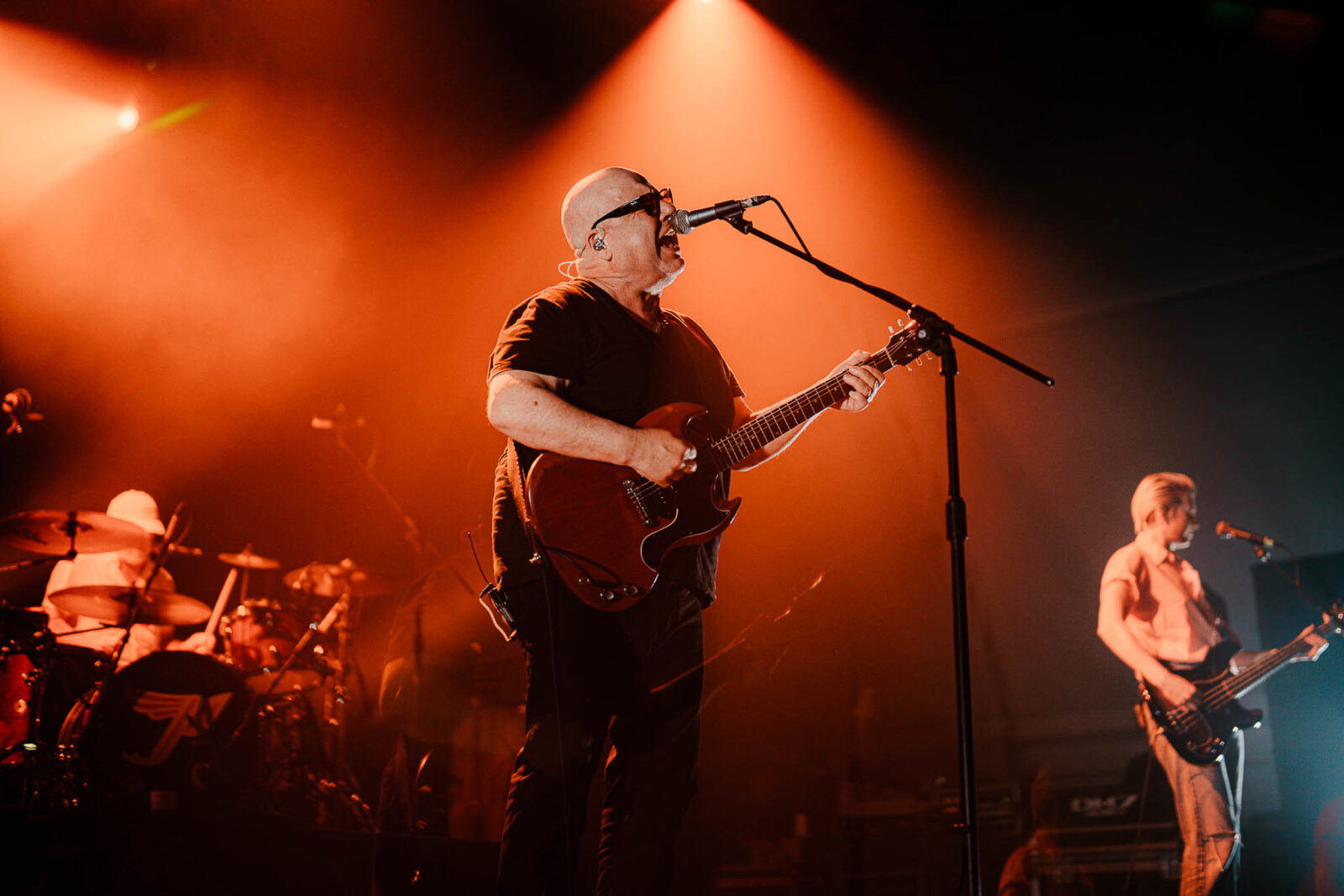 Lead guitarist and vocalist performing on stage under orange spotlight in a live concert